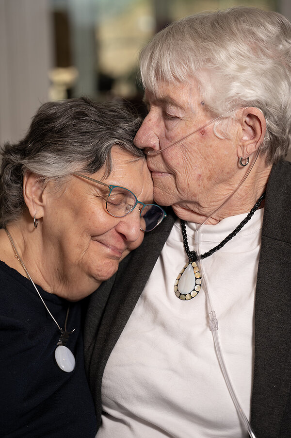 Carole Smith and Marj McCann embrace and smile in their home in the Kendal-Crosslands retirement community.